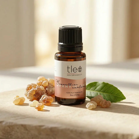 Bottle of tle essential oil with frankincense resin and a leaf on a light background