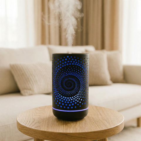Black cylindrical metal diffuser with blue spiral dot LED pattern misting on wood table, Aroma Paradise