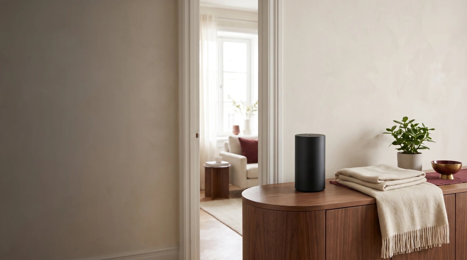 Compact black waterless diffuser on a walnut console in a bright apartment