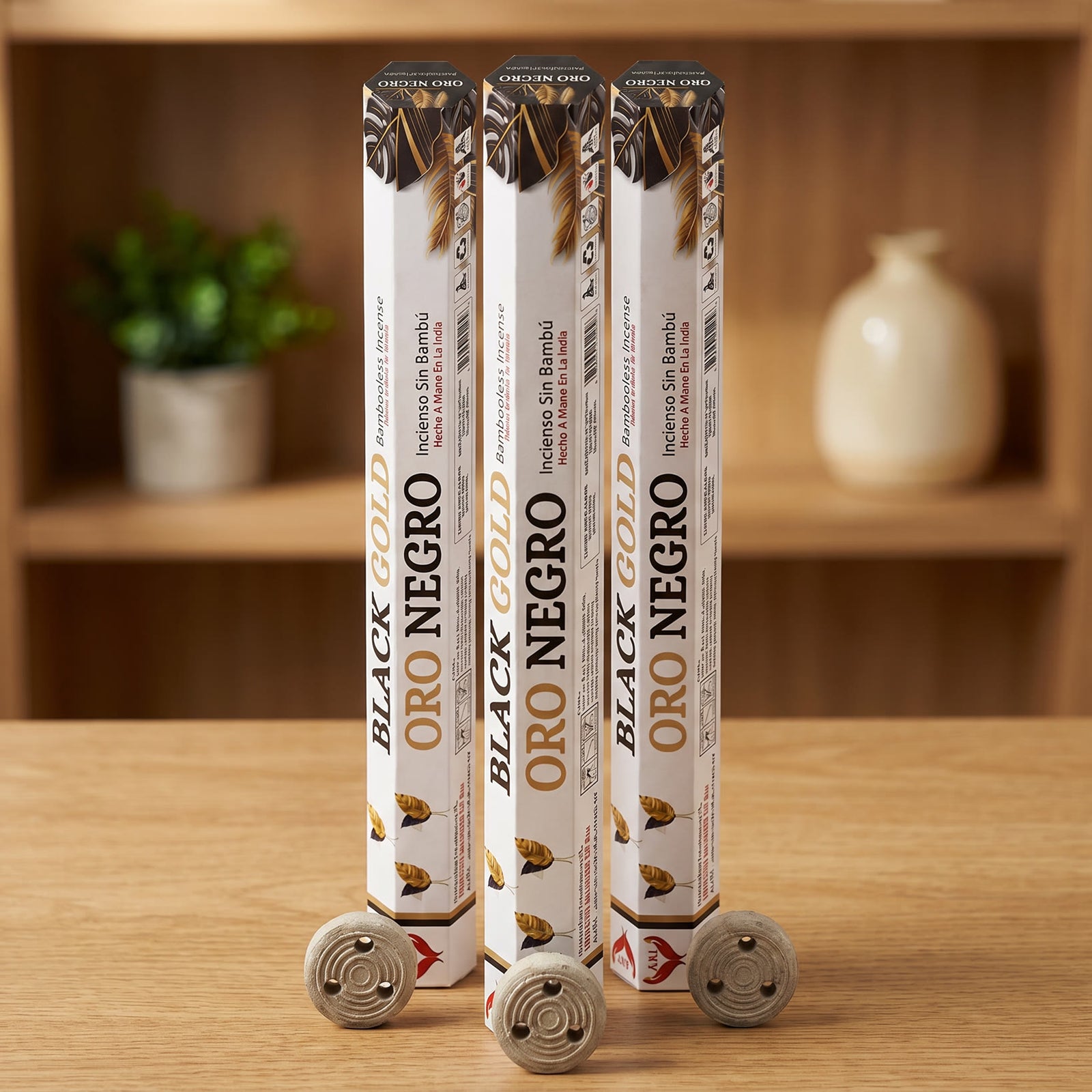 Aum Black and Gold bambooless incense sticks 3-pack with 3 metal coil holders on light oak wood surface