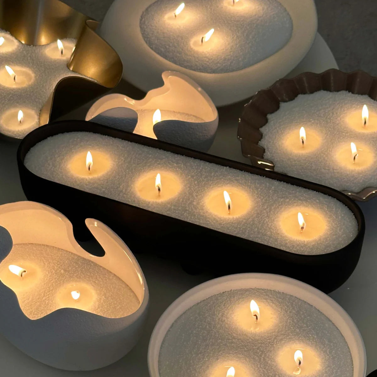 Pearled sand wax candle burning in decorative glass vessel