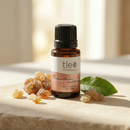 Bottle of tle essential oil with frankincense resin and a leaf on a light background