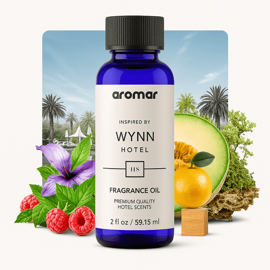 A bottle of 'Aromar Wynn Hotel' fragrance oil with an image of a luxurious resort background, flanked by a lemon and a green melon, with raspberries and greenery in the foreground.