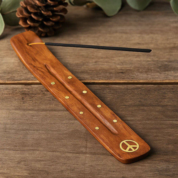 Wooden incense holder with peace symbol and black stick on a wooden surface
