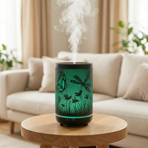 Black metal diffuser with green LED butterfly and dragonfly cutout patterns misting in living room, Aroma Paradise