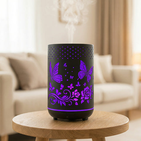 Black metal diffuser with purple LED butterfly and rose cutout patterns misting on wood table, Aroma Paradise