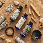 Good Luck Fragrance Oil Set flat lay with sage bundle, palo santo, bracelet on sandy surface - Aroma Paradise
