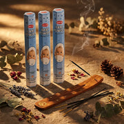Hem Baby Powder incense tubes with smoking stick in wooden holder on stone surface with botanicals - Aroma Paradise