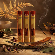 Hem Cinnamon incense tubes with smoking stick in wooden holder on stone with dried botanicals - Aroma Paradise