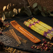 Hem Good Fortune incense tubes with smoking stick in wooden holder on dark slate with dried herbs - Aroma Paradise
