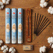 Hem Baby Powder incense flat lay with three tubes, wooden holder, sticks, and cotton on wood - Aroma Paradise