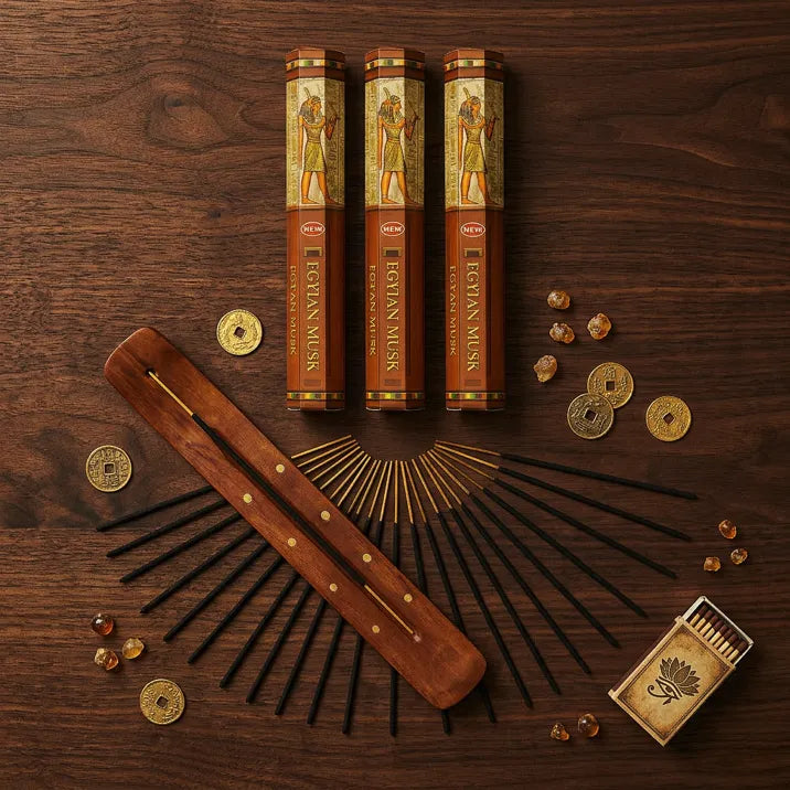 Hem Egyptian Musk incense flat lay with three tubes, wooden holder, sticks, and coins on dark wood - Aroma Paradise