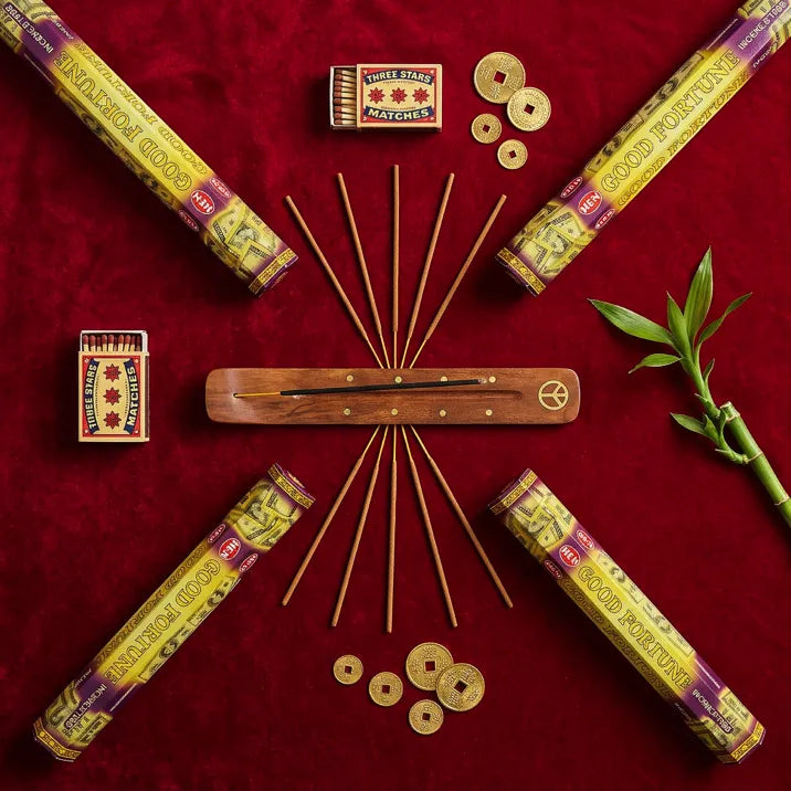 Hem Good Fortune incense flat lay with tubes, wooden holder, sticks, lucky coins, and bamboo on red velvet - Aroma Paradise