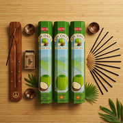 Three green Hem Coconut incense boxes with wooden holder, sticks, and matches on bamboo surface - Aroma Paradise