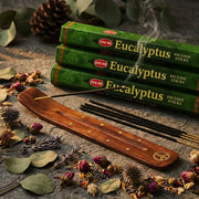 Three green Hem Eucalyptus incense boxes with smoking stick in wooden holder on stone with dried botanicals - Aroma Paradise