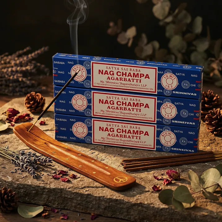 Three Satya Nag Champa blue boxes with smoking stick in wooden holder on stone with dried petals - Aroma Paradise