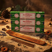 Three green Satya Patchouli incense boxes with smoking stick on wooden holder and dried flowers - Aroma Paradise