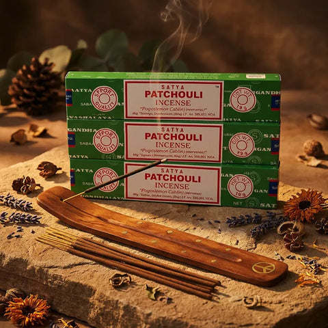 Three green Satya Patchouli incense boxes with smoking stick on wooden holder and dried flowers - Aroma Paradise