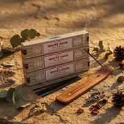 Three Satya White Sage incense boxes with smoking stick on wooden holder on stone with botanicals - Aroma Paradise