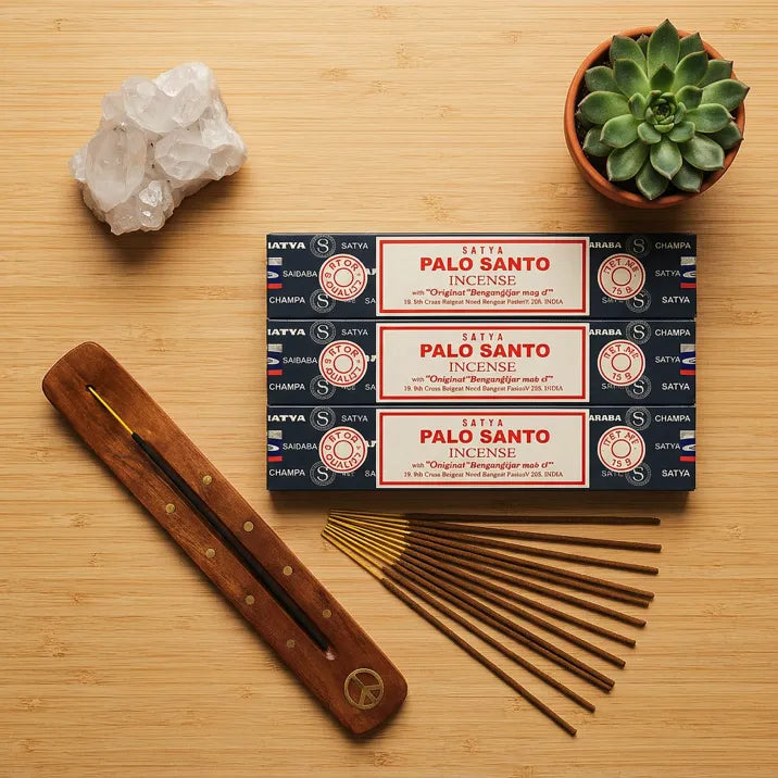 Three Satya Palo Santo incense boxes with wooden holder and sticks on bamboo surface - Aroma Paradise