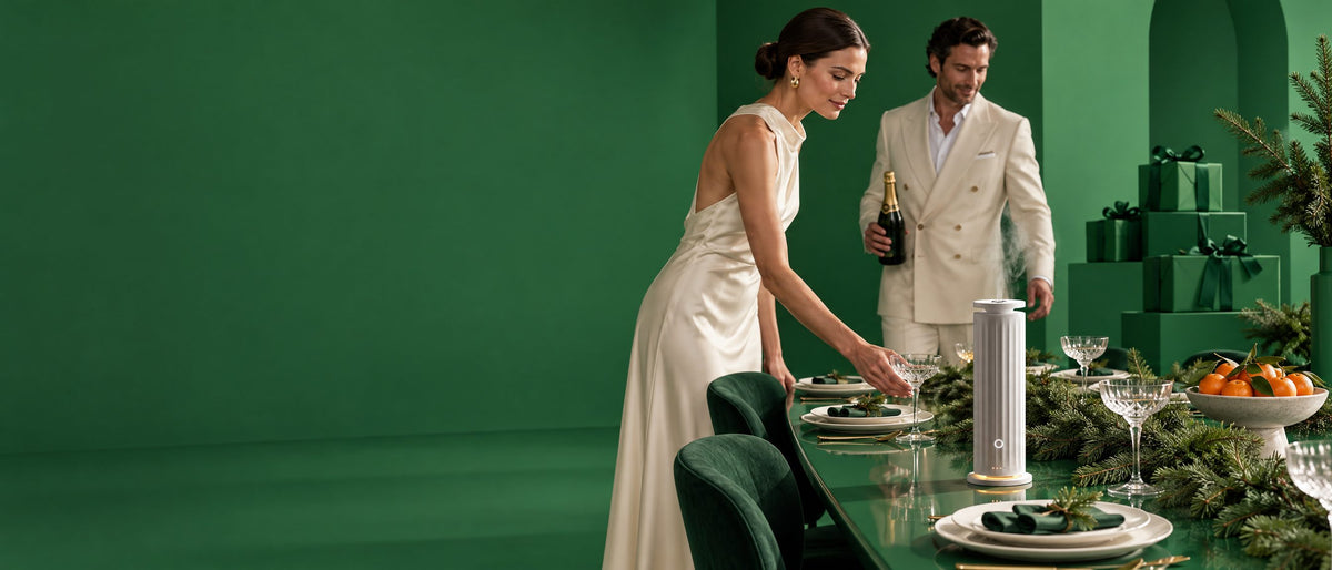 The Tower Pro waterless diffuser misting at the centre of a festive green dinner table as a host sets it