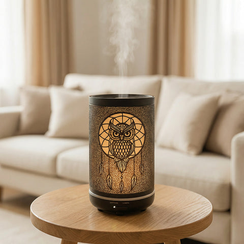 Black metal diffuser with warm gold owl dreamcatcher LED cutout pattern misting on wood table, Aroma Paradise